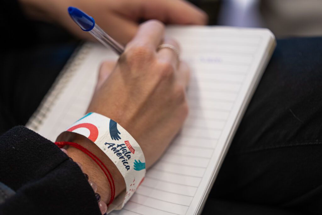 Libreta de persona tomando nota con pulsera en el Festival Hola América